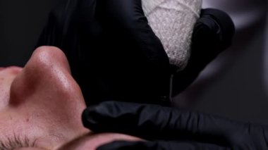 Dövme ustasının ellerinde kaş dövmesi dövme prosedürünü gerçekleştirir. Kaş dövmesi prosedürünü..