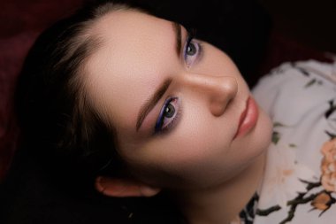 Stüdyonun rahat atmosferinin tadını çıkaran genç bir kadın, mükemmel yeni dövmeli kaşlarını gösteriyor..