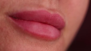 Dövmeden bir ay sonra dudaklarını yalayan bir kadının yakın çekimi. Dudaklar tamamen iyileştikten sonra doğal renk ve kalıcı pigmentler görünür..