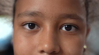 Genç Afrikalı kızların yakın çekimleri kameraya bakan güzel siyah gözlerle yanıp sönüyor. Ağır çekim. Yüksek kalite 4k görüntü