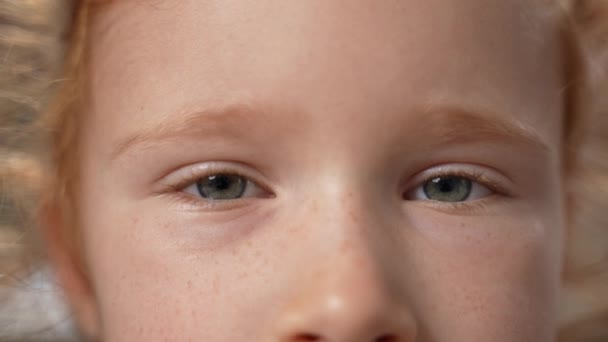 小さなジンジャーの女の子の近くにカメラを見ている美しい灰色の目で点滅する顔 子供達はフリュックルを見ている スローモーション 高品質の4K映像 — ストック動画