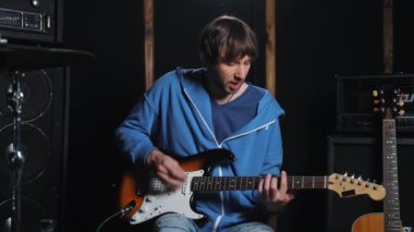 Online müzik dersi sırasında, gitar öğretmeni elektro gitar ve akorlar hakkında açıklama yapar, stüdyoda çevrimiçi müzik kursları kaydeder.. 