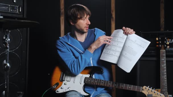 Nauczyciel Gitary Patrząc Aparat Pokazując Książkę Muzyczną Akordami Opisując Jak — Wideo stockowe