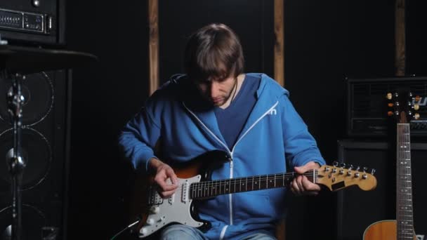 サウンドレコーディングスタジオでエレクトリックギターで演奏するミュージシャンの映像 リハーサルスペースのバックグラウンドで楽器で演奏するプロのギタリスト — ストック動画
