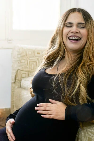 Mujer Embarazada Sonriendo Cámara Mientras Una Sus Manos Toca Vientre —  Fotos de Stock