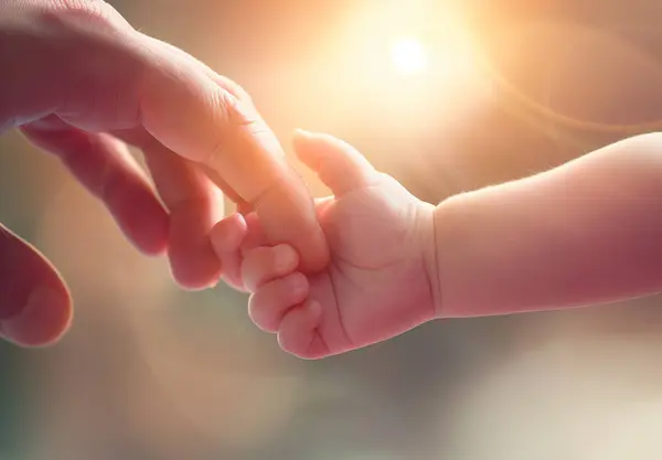 Bebeğin elini tutan bir yetişkinin eli, babalık ya da annelik.