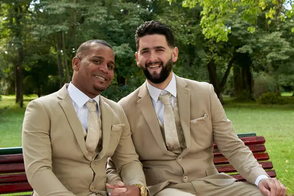 Eşcinsel topluluğundan yeni evli bir çiftin portresi. İkisi de resmi kıyafetler giyip kameraya gülümsüyor ve el ele tutuşuyorlar..