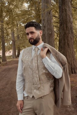 Bir sonbahar günü takım elbiseli ve kravatlı bir adamın kameraya baktığı Amerikan fotoğrafı. Bir doğa geçmişi var.