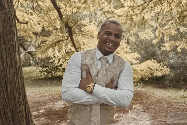 Latin adam kameraya gülümsüyor, kollarını kavuşturmuş duruyor. Sonbahar mevsimi konsepti, insan mutludur..