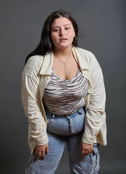 Genç kız fotoğraf stüdyosunda poz veriyor, üzerinde zebra hayvan desenli tişört ve kot pantolon var..