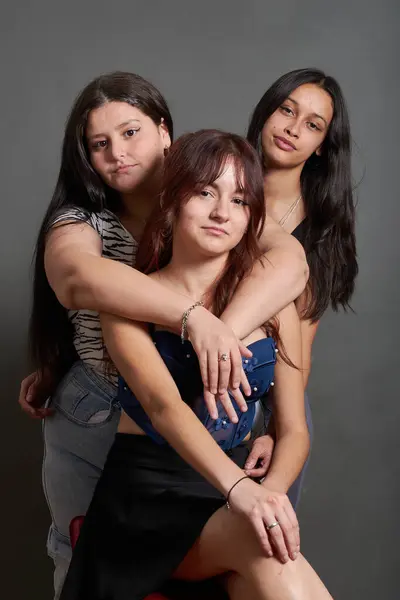 Üç genç arkadaştan oluşan bir grubun portresi, kameraya bakıyorlar, Latinler, fotoğraf bir stüdyoda çekildi. Çeşitli vücutlar var, bir kız aşırı kilolu, diğeri çok sıska, ve diğeri kızıl saçlı..