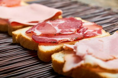 Dokuma hasırının üzerinde çeşitli kesiklerle örülmüş bir ekmek dilimleri. Dokuları ve renkleri vurgulamak için yakın plan. Gıda veya editoryal içerik için ideal.