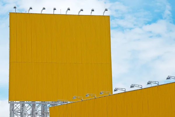 Bulutlu gökyüzü ile boş sarı şerit ilan panosu.