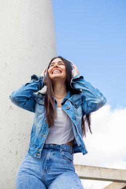 Gülümseyen ve kablosuz kulaklıkla müzik dinleyen güzel bir genç kız. Yüksek kalite fotoğraf