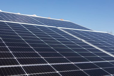 Kırmızı çatıdaki güneş paneli güneşi ve arkadaki bulutlu mavi gökyüzünü yansıtıyor. Yüksek kalite fotoğraf