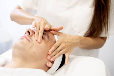 Güzellik uzmanının elleri orta yaşlı bir adama yüz masajı yaparken. Cilt bakımı. Yüksek kalite fotoğraf