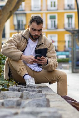 Beklerken cep telefonuyla konuşan genç bir adamın portresi. Yüksek kalite fotoğraf