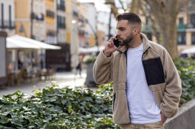 Beklerken cep telefonuyla konuşan genç bir adamın portresi. Yüksek kalite fotoğraf