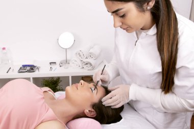 Estetisyen, kirpik kaldırma işlemine devam etmesi için göz kapağı koruyucusunu uyguluyor. Yüksek kalite fotoğraf