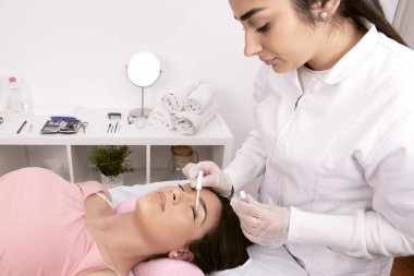 Estetisyen, kirpik kaldırma işlemine devam etmesi için göz kapağı koruyucusunu uyguluyor. Yüksek kalite fotoğraf