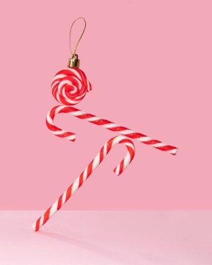 Pastel açık pembe arka planda dengede duran baston şekerler. Minimalist Xmas kompozisyonu. Geleneksel Noel konsepti. Minimalist kış tatili tebrik kartı. Yaratıcı yeni yıl fikri.