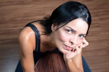 Studio portrait of young woman in black t-shirt looking at camera against wooden floor on floor. Salvador, Brazil.
