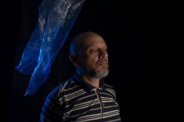 Yüzünün üzerinde uçuşan şeffaf, mavi bir çanta taşıyan olgun bir adam. Boğularak. Yüzü plastik torbada, boğulma.