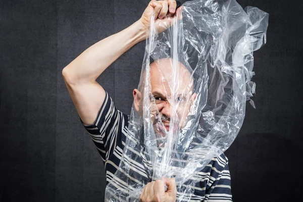 Mature man with a transparent plastic bag flying over his head and face. suffocate. face in a plastic bag, strangulation