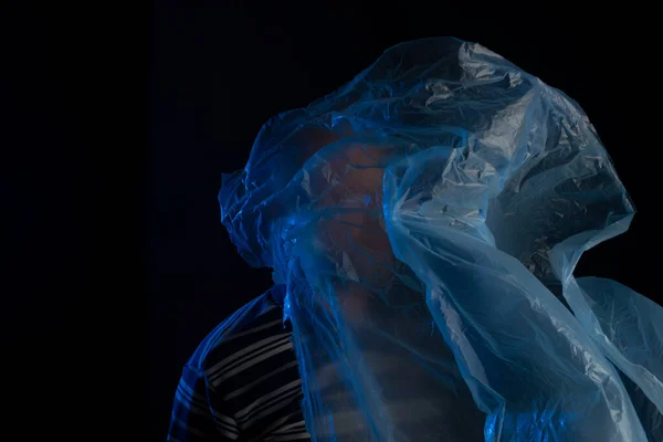 Mature man with a transparent plastic blue bag flying over his head and face. suffocate. face in a plastic bag, strangulation