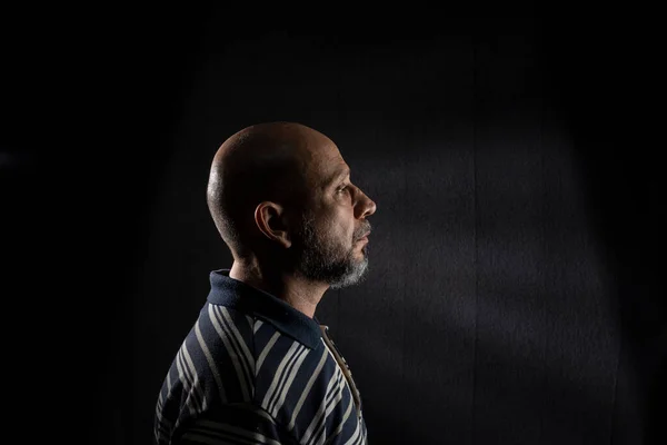 Young handsome bald man with beard wearing casual shirt over black background. Thinking worried. Thoughtful.