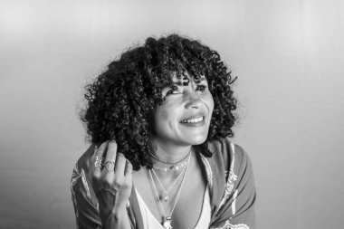 Hafif arka planda gülümseyen kıvırcık saçlı güzel modelin portresi. Olgun bir kadın. Özsaygı kavramı.