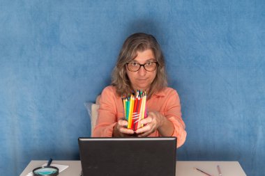 Ev ya da ofisten çalışan dizüstü bilgisayarlı renkli kalemler gösteren bir kadın. İş, insan ve teknoloji kavramı.