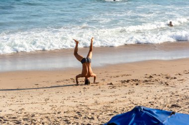 Salvador, Bahia, Brezilya - 22 Ekim 2022: Bir adam Brezilya 'nın Salvador kentindeki Farol da Barra plajında yoga yapıyor..