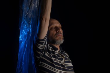 Yüzünün üzerinde uçuşan şeffaf, mavi bir çanta taşıyan olgun bir adam. Boğularak. Yüzü plastik torbada, boğulma.