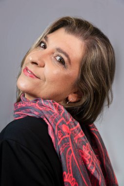 Güzel, gülümseyen bir kadın, ışık stüdyosunda izole edilmiş kameraya bakıyor..