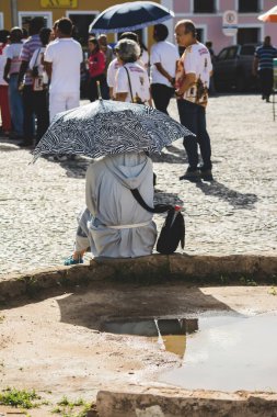 Salvador, Bahia, Brezilya - 26 Mayıs 2016: Brezilya 'nın Salvador kentindeki Corpus Christ ayini sırasında Katolik bir keşiş sokakta oturuyor.