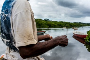 Aratuipe, Bahia, Brezilya - 31 Ağustos 2018: Balıkçı, Bahia 'nın Aratuipe kentindeki Jaguaripe nehrinin kıyısında balık yakalamak için yem atıyor.