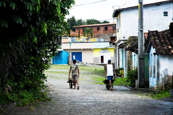 stock image Aratuipe, Bahia, Brazil - August 31, 2018: Two men, workers, carrying goods to the store through the streets of Aratuipe, Bahia.