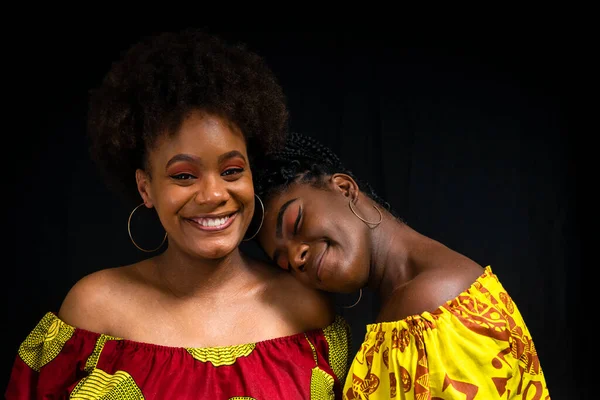 stock image Portrait of two women against black background. One of them rests her head on the others shoulder. Friendship concept.