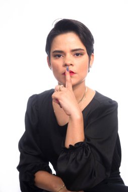 Genç, zarif iş kadını parmakları ağızda sessizlik işareti yapıyor. Beyaz arkaplanda izole.