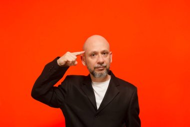 Modaya uygun bir iş adamının el hareketleriyle portresi. Kameraya bakıyorum. Turuncu arka planda izole edilmiş.