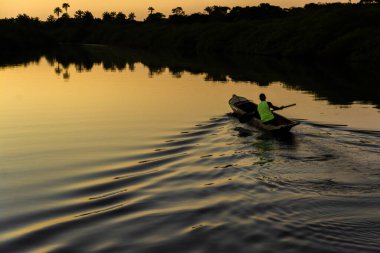 Aratuipe, Bahia, Brezilya - 31 Ağustos 2018: Gün batımında bir balıkçı kanosunu Jaguaripe Nehri 'nde yüzdürüyor..