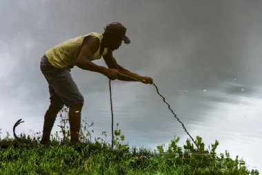 Aratuipe, Bahia, Brezilya - 31 Ağustos 2018: Bahia 'nın Aratuipe kentindeki Jaguaripe Nehri kıyısında ip çeken bir adamın sudaki yansıması.