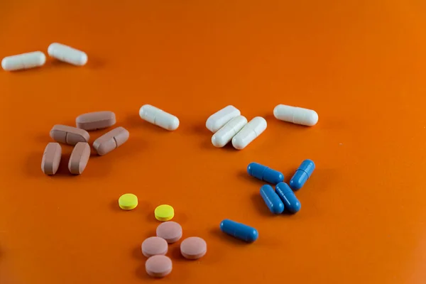 不同的棕色 蓝色和黄色药丸散布在橙色背景上 医疗用品 — 图库照片
