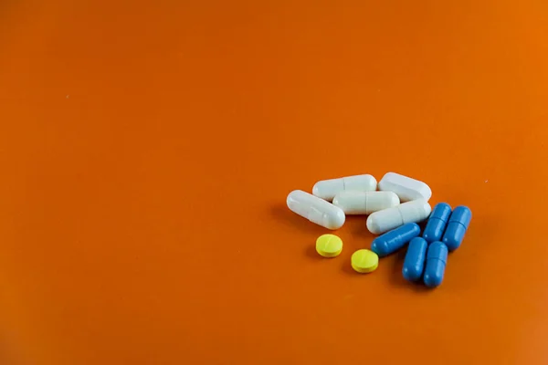 在橙色背景下堆装药丸医疗用品 — 图库照片