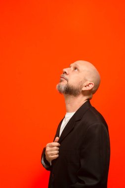 Yukarı bakan zarif bir iş adamının portresi. Turuncu arka planda izole edilmiş.