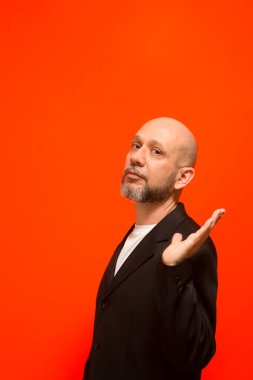 Modaya uygun bir iş adamının el hareketleriyle portresi. Kameraya bakıyorum. Turuncu arka planda izole edilmiş.