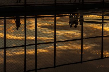 Salvador, Bahia, Brezilya - 05 Aralık 2021: Salvador, Bahia 'da Rio Vermelho plajında günbatımına karşı egzersiz yapan insanların siluetinin yansıması.