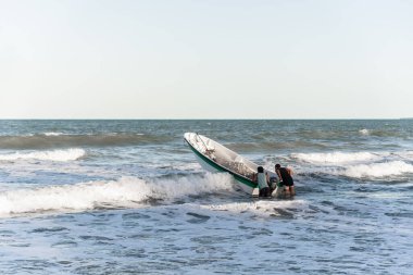 Valenca, Bahia, Brezilya - 10 Eylül 2022: Bir motorlu tekneyle deniz dalgalarından geçen iki adam. Guaibim Plajı, Valenca, Bahia.