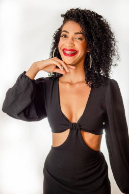 Neşeli genç bir kadın, sakin, eli çenesinde, kameraya bakarak gülümsüyor. Stüdyoda beyaz arka planda izole edilmiş.